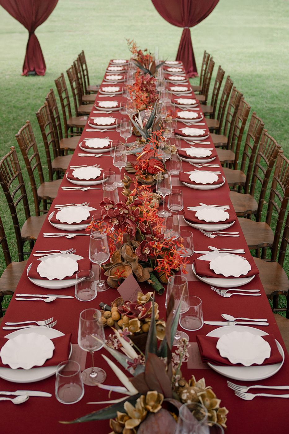 Long outdoor banquet table with wavy-edge plates and orchid centerpieces