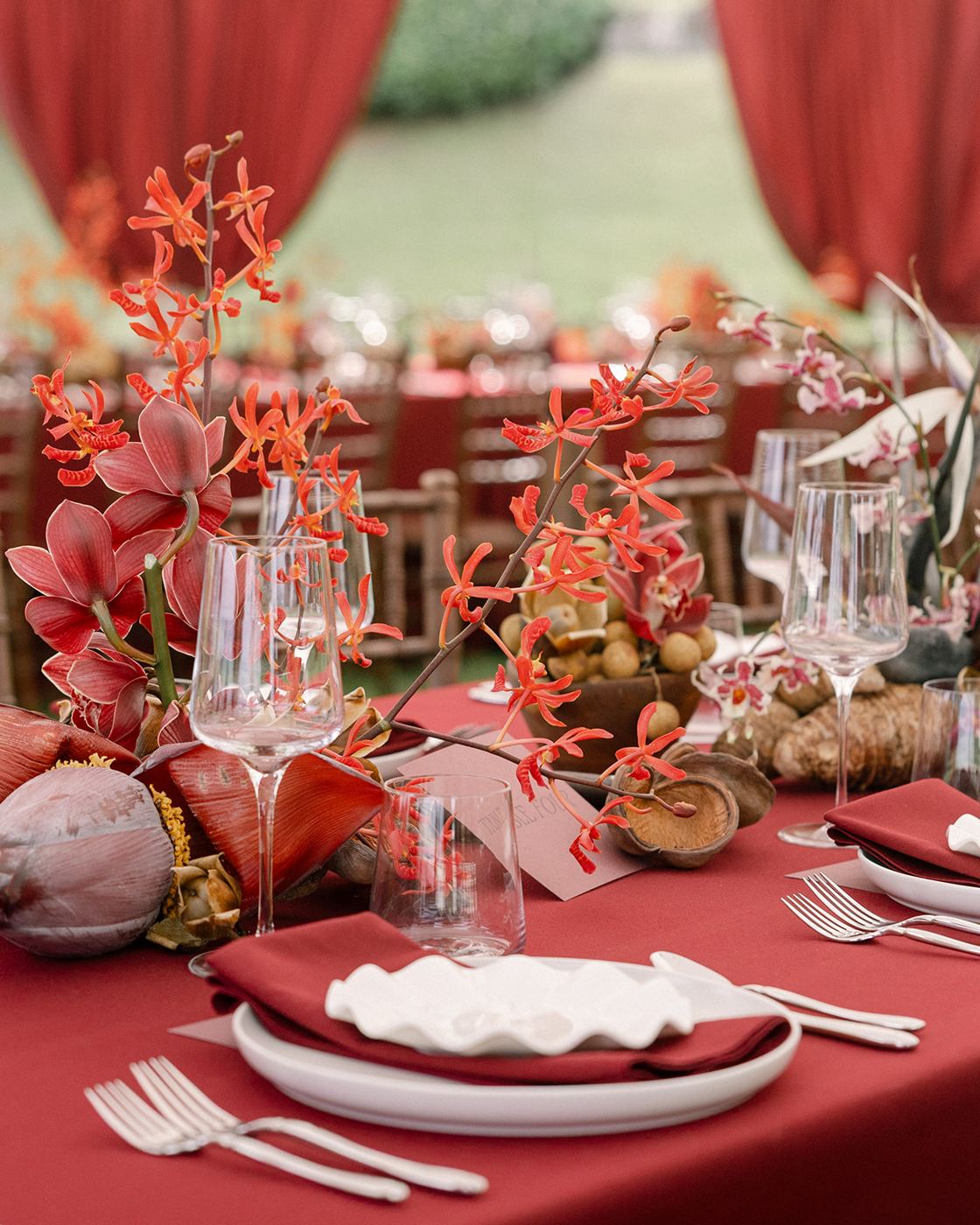 Orchid centerpiece and stemware on a burgundy table