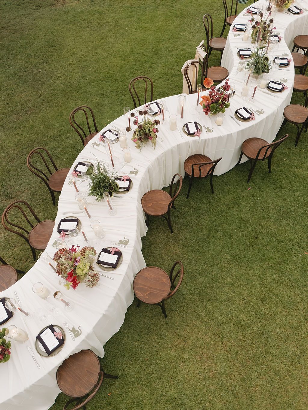 Curved reception table from above with Ivy plates, plum napkins and taper candles